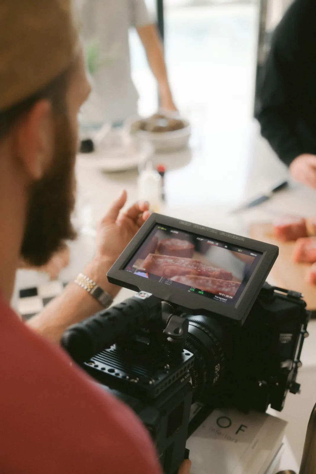 Videomaker de costas conferindo o monitor da câmera durante uma gravação